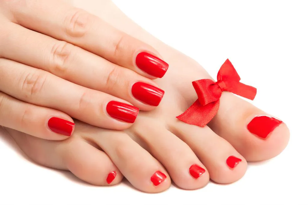 Red manicure and pedicure with a bow